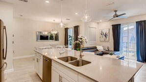 A modern kitchen with a large island, stainless steel appliances, pendant lighting, and a view to the outside. - 4808 LL Magical 4BR Disney Townhome Pool (Kissimmee)