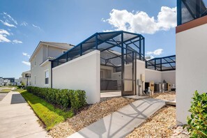 Un immeuble résidentiel moderne doté d’un patio entièrement vitré, d’une allée et d’une pelouse bien entretenue.