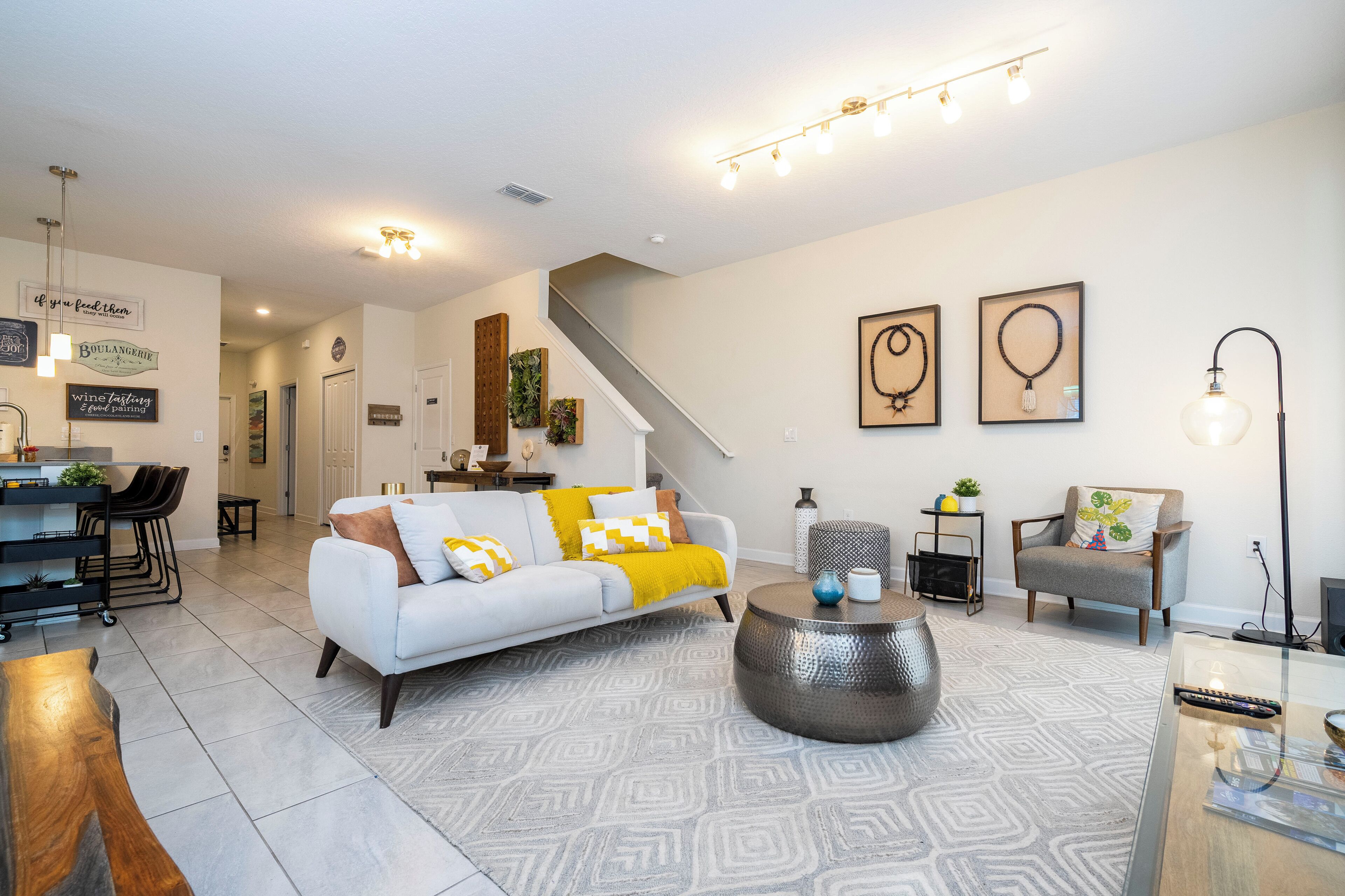 A modern living room with a white sofa, a coffee table, and a staircase leading to another level.