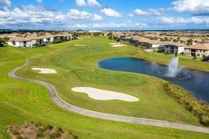 Ein Golfplatz mit Bunkern, einem Teich und einer Springbrunnen.