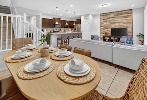 A modern kitchen with white cabinets, a central island, and a dining area with a round table set for four.