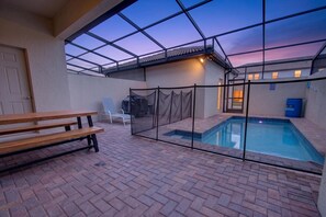 Un espace extérieur abrité comprenant une piscine, un banc en bois et une chaise.