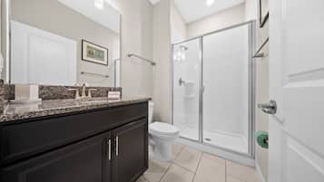 Een moderne badkamer met douche, toilet en wastafel.