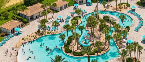 An aerial view of a resort with multiple swimming pools, sun loungers, and palm trees.