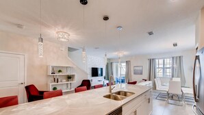 Een moderne keuken met een centraal eiland, roestvrijstalen apparatuur en hanglampen.