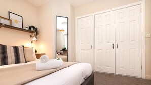 A neatly arranged bedroom with a bed, bedside table, lamp, and a wardrobe. - Splendid Apartment near City Centre (Edinburgh)