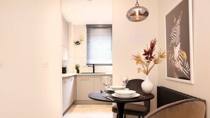A dining area with a table set for two, a vase with flowers, and a zebra-themed artwork on the wall. - Splendid Apartment near City Centre (Edinburgh)