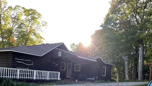 A wooden cabin with a white picket fence, a picnic table, and outdoor chairs. - Chapel Hill Resort (Spring Lake)