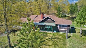A log cabin with a green roof, a chimney, and a porch with chairs. - Chapel Hill Resort (Spring Lake)