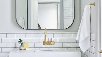 A bathroom with a white marble sink, gold faucet, and a white towel hanging on a gold towel rack.