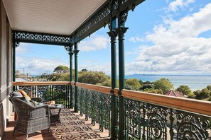 Een balkon met rieten meubilair en uitzicht op zee.