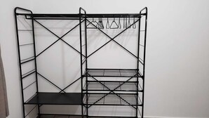 A black metal shelving unit with multiple shelves and hooks for hanging items. - Spacious, beautiful apartment - 3 blocks from the beach! (Guarujá)