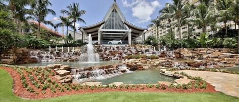 Un hotel con una gran cascada, palmeras y un jardín bien cuidado.