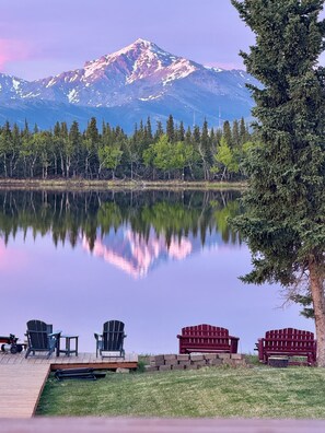 A lakeside view with a mountain in the background, a dock with chairs and a bench, and a tree on the right. - Lake House Family Retreat @ Denali Nat'l Park. Hot (Healy)