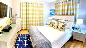 A bedroom with a bed, nightstands, a desk, and curtains. - Oceanfront Paradise w new 365' Dock Huge Tiki and Firepit.  Dogs OK (Big Pine Key)