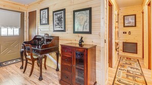 A wooden interior with a piano, a cabinet, and framed artwork on the walls.