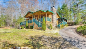 A lodge with a porch, a stone chimney, and a wooden deck.
