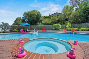 A swimming pool with pink flamingo floats and a hot tub.