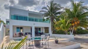 A modern two-story house with a pool, outdoor seating, and palm trees. - Casa Nazul  -  Yucatan Home Rentals (Chicxulub Puerto)
