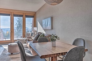 Un comedor moderno con una mesa de madera, sillas tapizadas en gris y una planta en maceta.