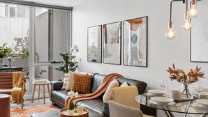 A modern living room with a leather sofa, a glass coffee table, and abstract wall art. - Ultimate Comfort Gem in St Kilda  ⭐⭐⭐⭐⭐ (St Kilda)