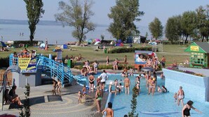 A public swimming pool with a slide, surrounded by trees and a grassy area. - Holiday apartment with wifi and parking (Balatonboglár)