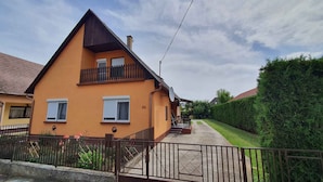 A two-story house with a balcony, a visible number '32', and a well-maintained garden. - Holiday apartment with wifi and parking (Balatonboglár)