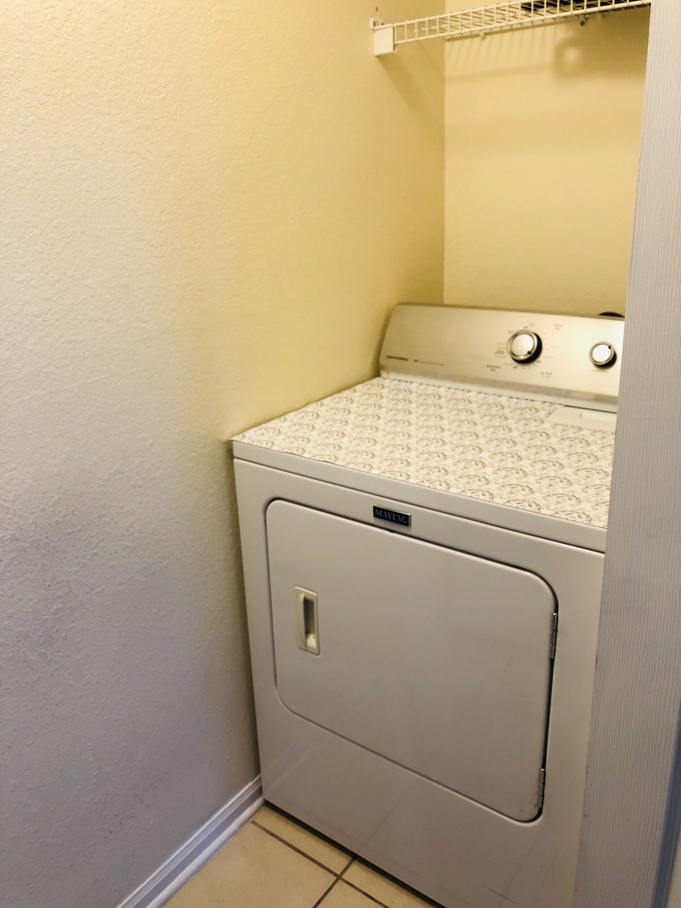 A compact, white, wall-mounted washer and dryer unit with a patterned top.