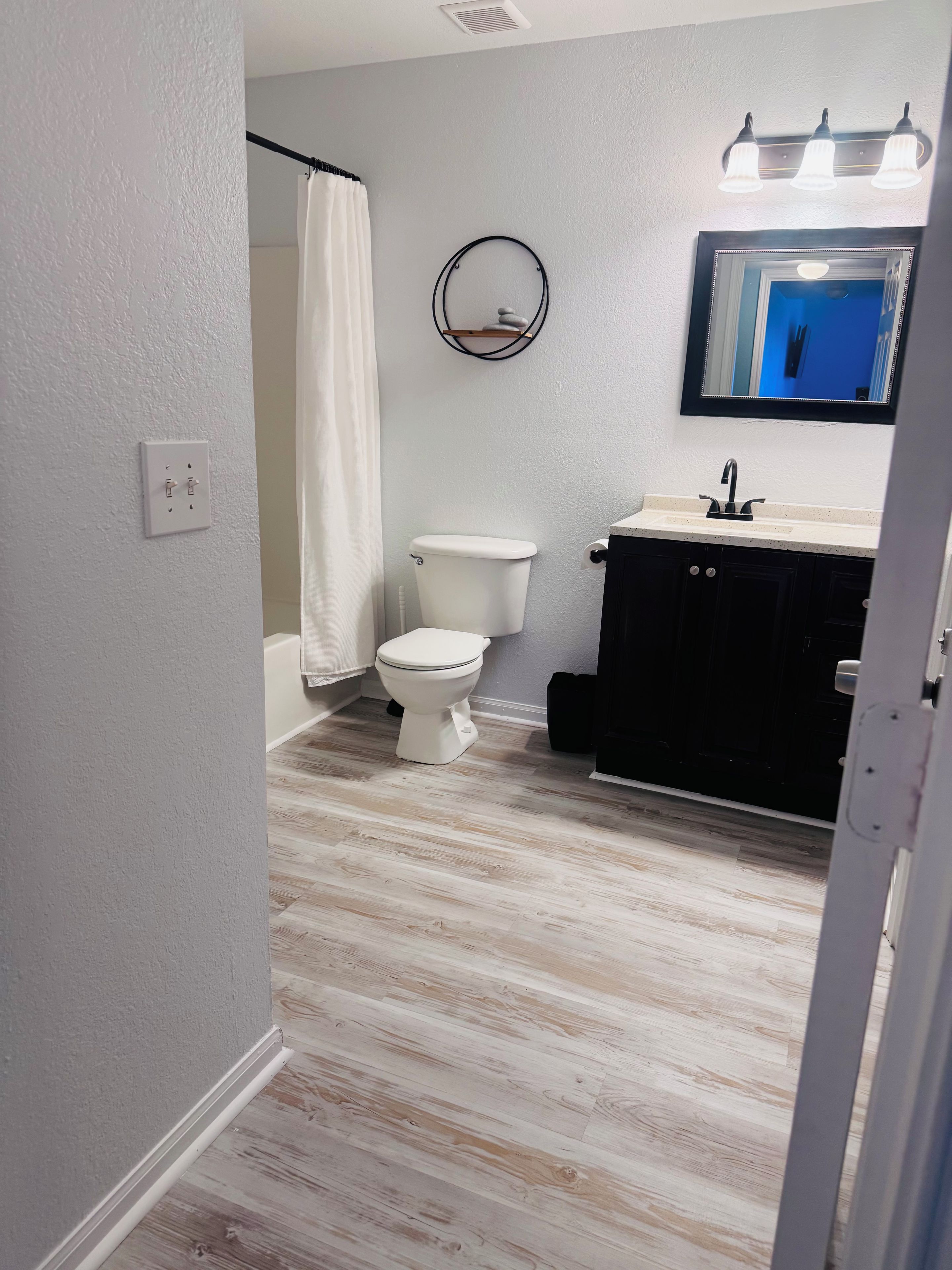 A bathroom with a toilet, sink, and a mirror.