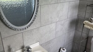 A bathroom with a round mirror, a sink, a toilet, and a towel rack.