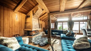 Un interior de cabaña acogedor, con un sofá azul grande, una chimenea de piedra y paredes de madera.