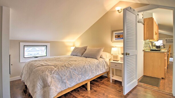 A bedroom with a bed, bedside table, lamp, and a view of the kitchen through an open door. - Idyllic Wallingford Retreat - Near Skiing & Hiking (Wallingford)