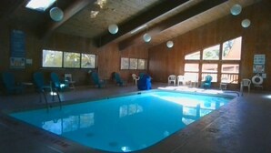 An indoor swimming pool with wooden walls and ceiling, surrounded by chairs and tables. - Cedar Village Condo A5, Beech Mountain, NC (Beech Mountain)
