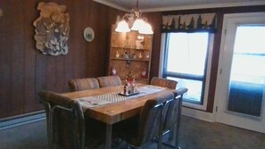 A dining room with a wooden table, cushioned chairs, and a chandelier.