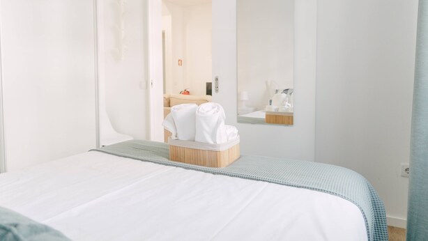 Et hotelværelse med en seng, et træsidebord og et spejl på væggen.