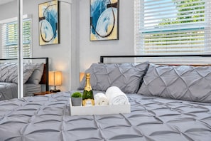 A hotel room with a large bed, a bottle of champagne, and a tray with towels.