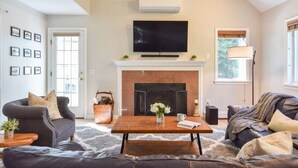 A living room with a fireplace, a television mounted above it, and a sofa. - Peaceful retreat plus Dog Friendly! (Wellfleet)