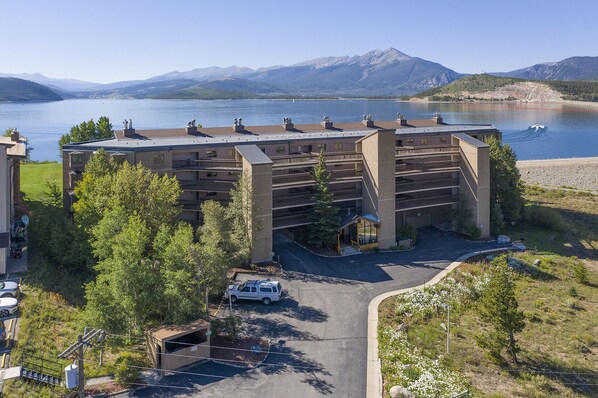 Un parking à étages situé à côté d’une étendue d’eau, avec des montagnes en arrière-plan.