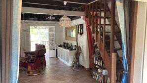 Een ruime woonkamer met een rode leren fauteuil, een houten boekenkast en een trap.