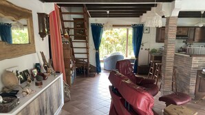 Een ruime woonkamer met een rode leren bank, een houten trapje en een keuken die zichtbaar is door een open doorgang.