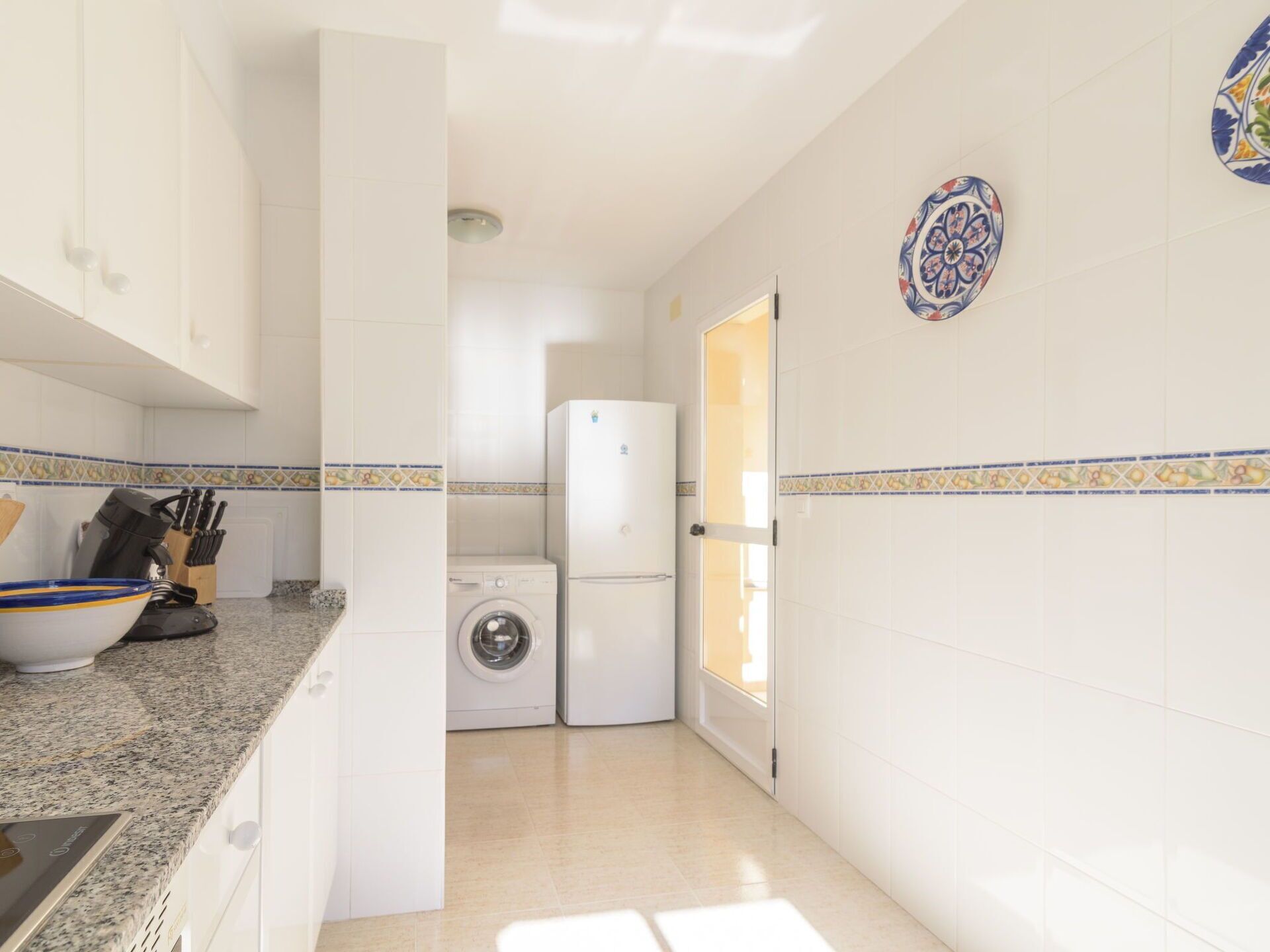 A compact kitchen with white cabinets, a washing machine, and a refrigerator.