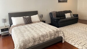 A bedroom with a bed, a nightstand, a lamp, a sofa, and a rug. - Cozy Luxury Suite In The Heart Of Fort Myers Close To Everything! (Fort Myers)