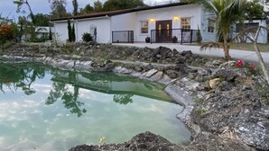 A house with a swimming pool, surrounded by rocks and trees. - Cozy Luxury Suite In The Heart Of Fort Myers Close To Everything! (Fort Myers)