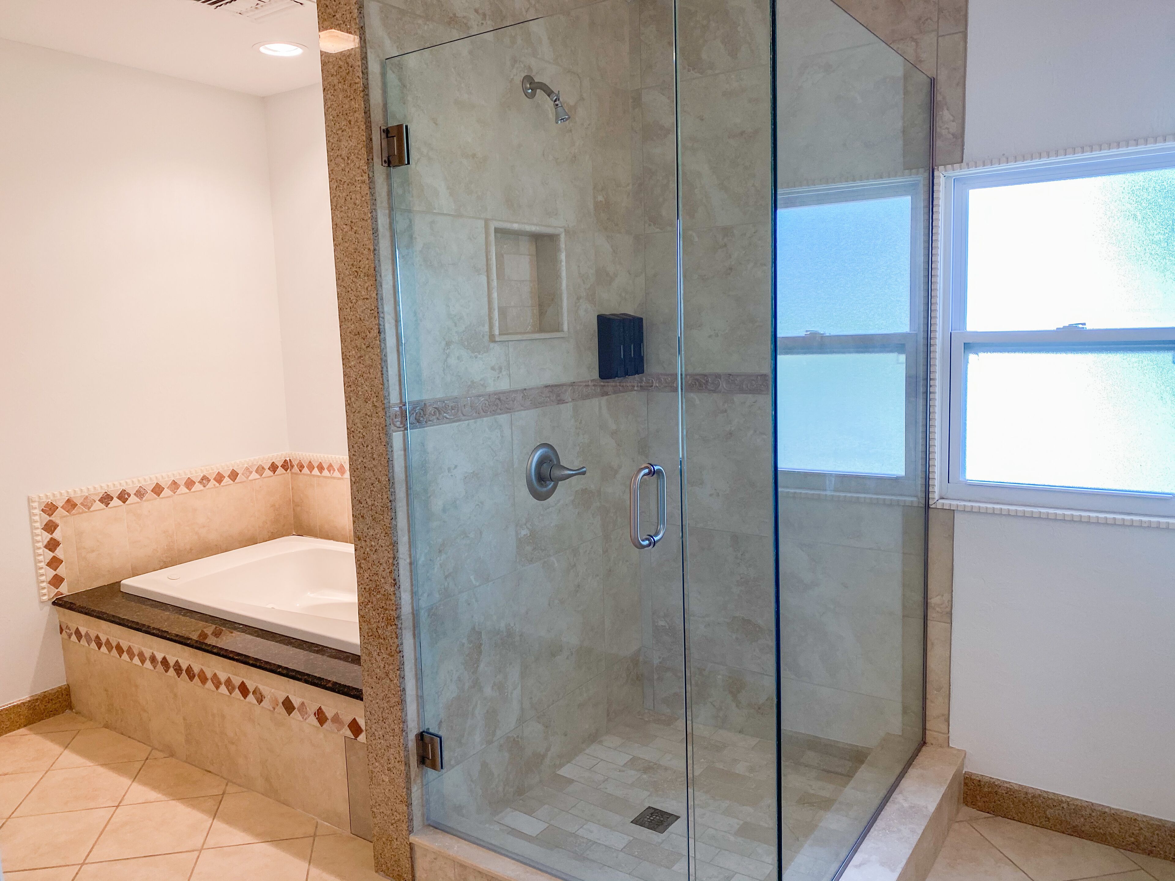 Une salle de bain moderne dotée d’une douche à parois de verre, d’une baignoire et d’une fenêtre offrant une vue agréable.