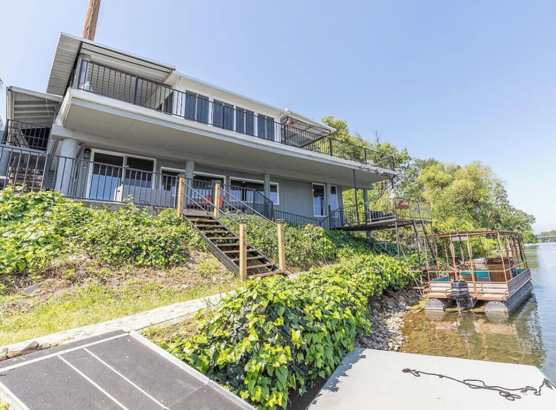 A modern two-story house with a balcony, a dock, and a boat.