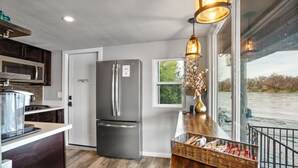 Una cocina moderna con un refrigerador de acero inoxidable, una encimera de madera y vista a un río.