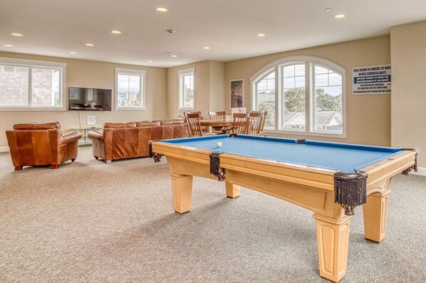 A pool table in a room with beige carpet, a brown leather sofa, and a dining table with chairs. - Pacific Pearl Condo, Hot Tub & Panoramic Views (Lincoln City)