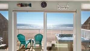Une vue sur la plage depuis une chambre dotée d’une grande fenêtre, d’une horloge et d’un panneau indiquant « plage ».
