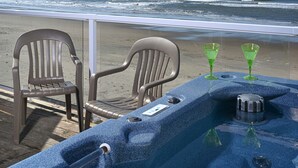 Une table installée sur la plage, avec deux chaises et deux verres verts, d’où l’on a une vue sur l’océan.