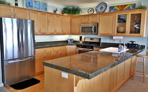 A modern kitchen with wooden cabinets, stainless steel appliances, and a granite countertop.